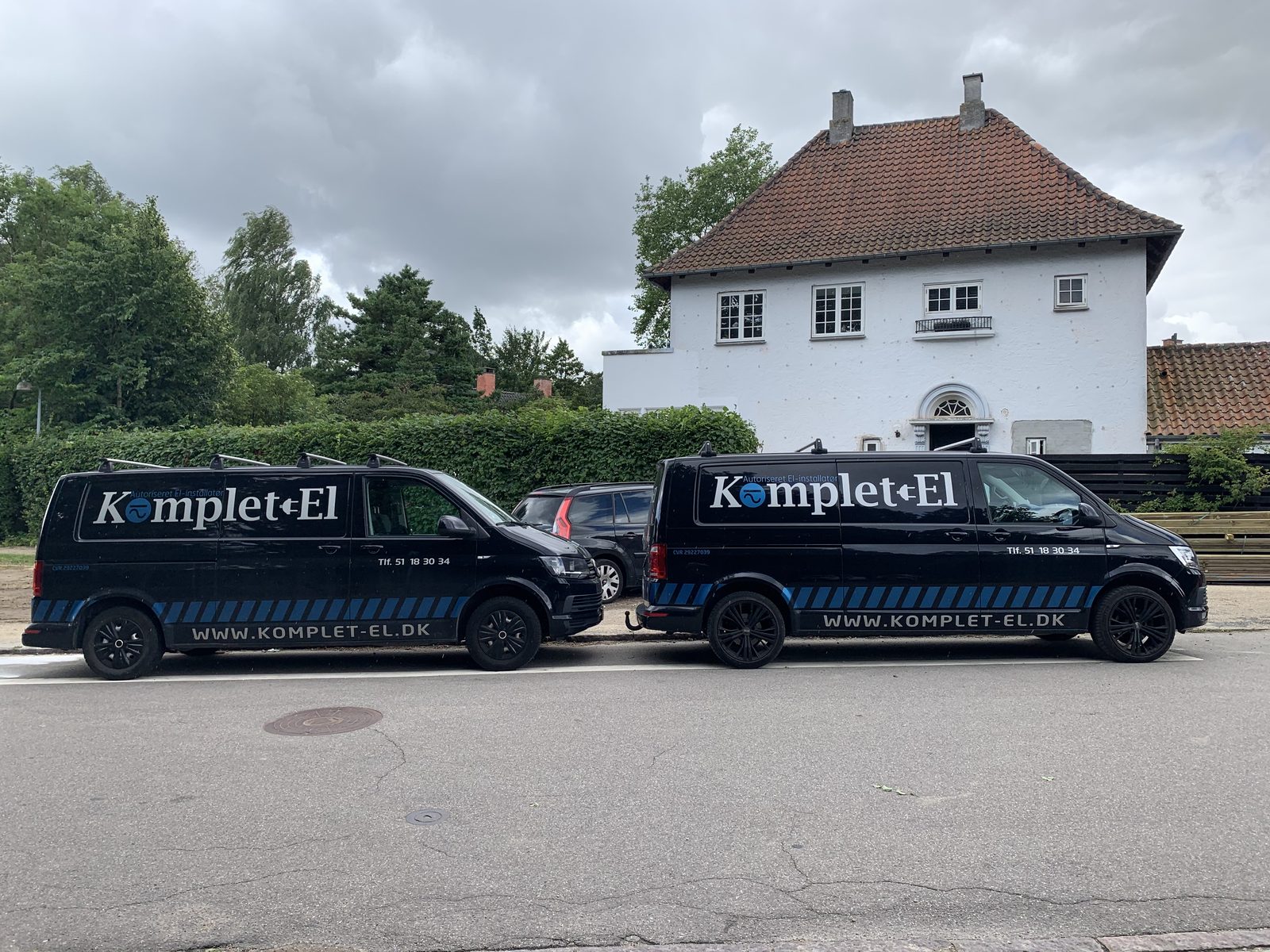 Servicebiler fra Komplet-El holder foran et hus
