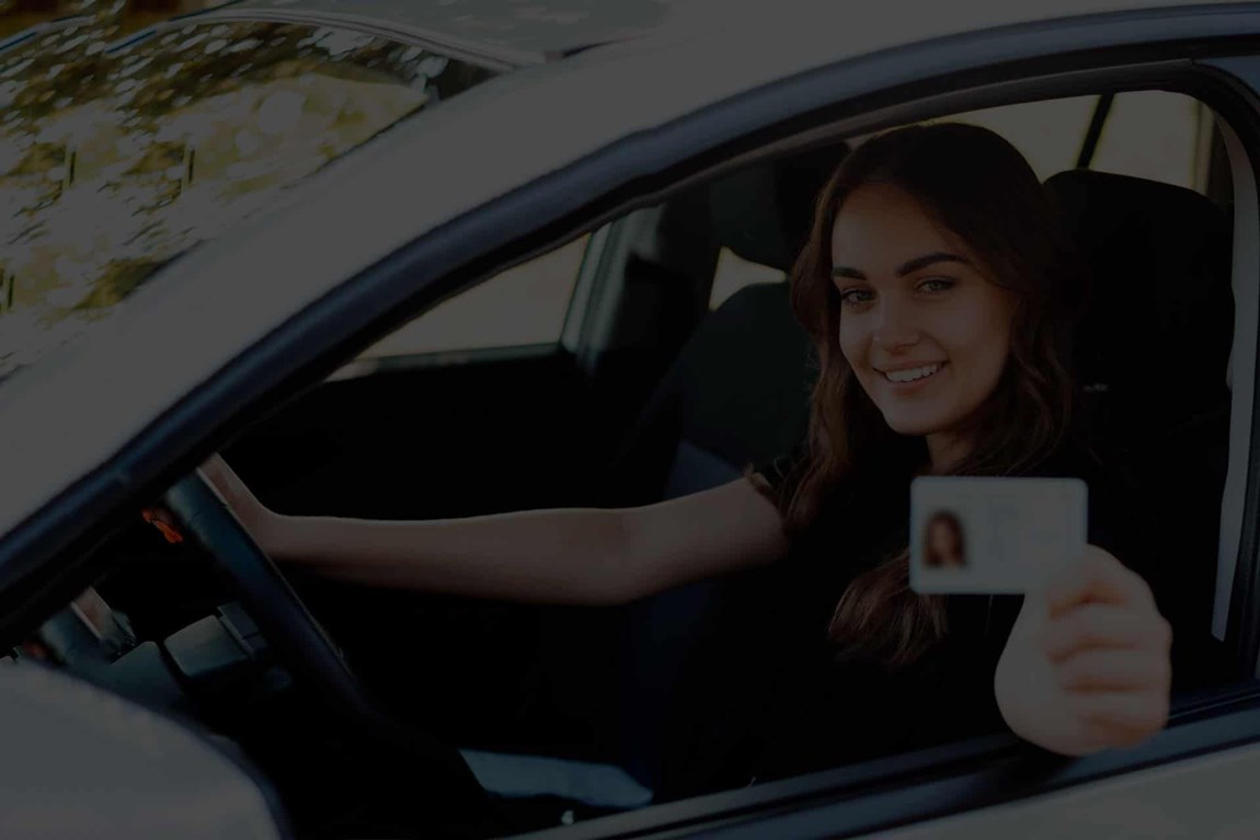 Kvinde ved rattet der viser sit kørekort